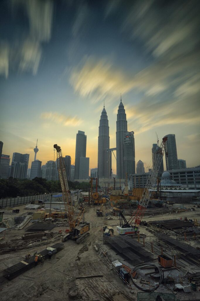 pexels-photo-190417-190417 Dramatic view of the Petronas Towers towering over a busy construction site in Kuala Lumpur at sunset.